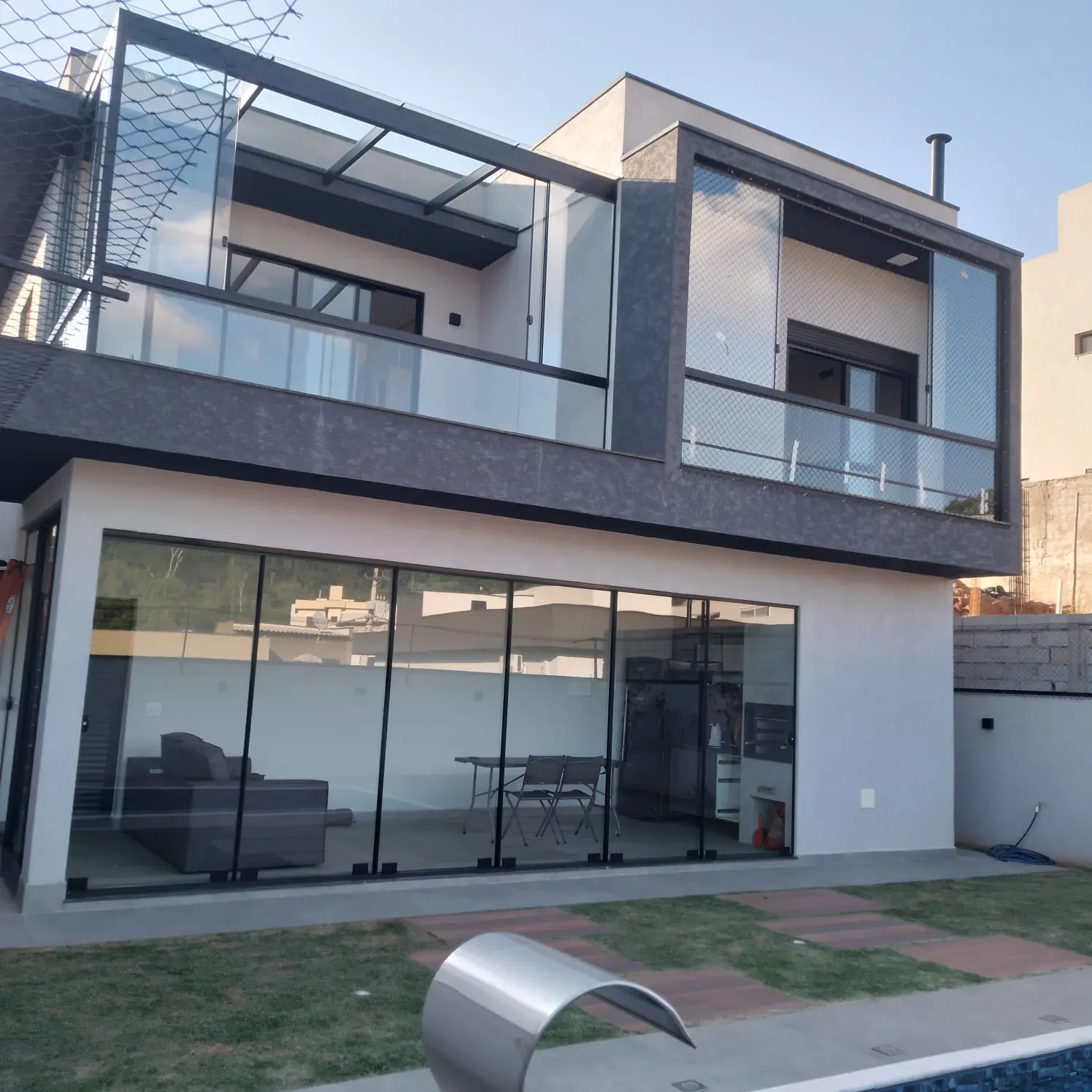 Casa com fachada envidraçada e vista para piscina, com esquadrias de alumínio