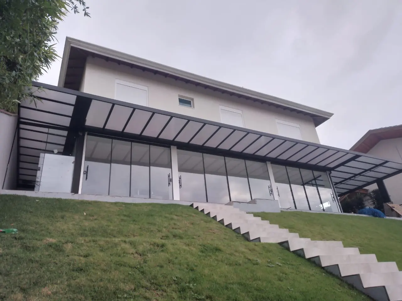 Cobertura de vidro laminado sobre área externa, com estrutura de alumínio