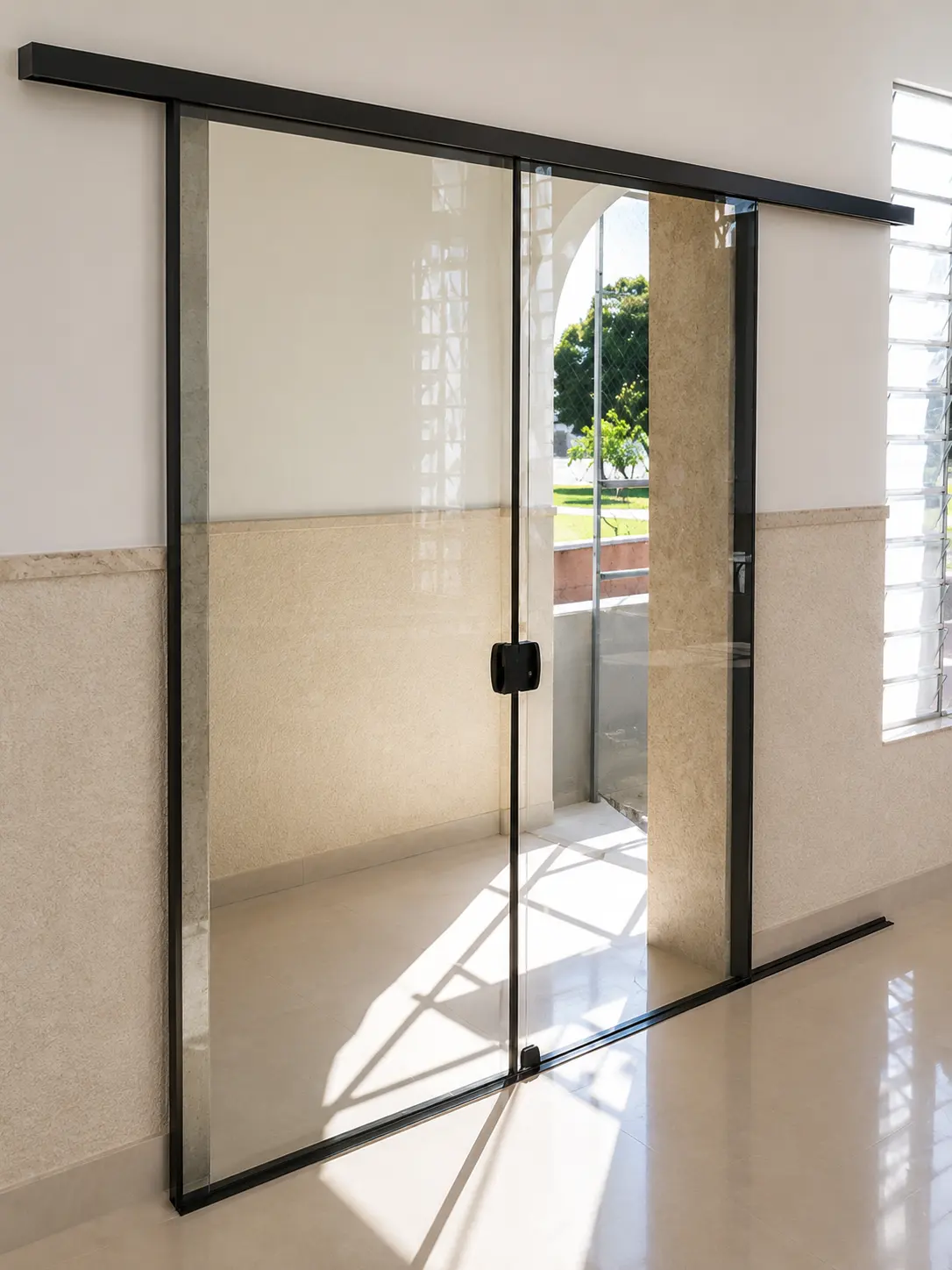 Porta de vidro temperado com dobradiças pretas, dividindo ambientes internos