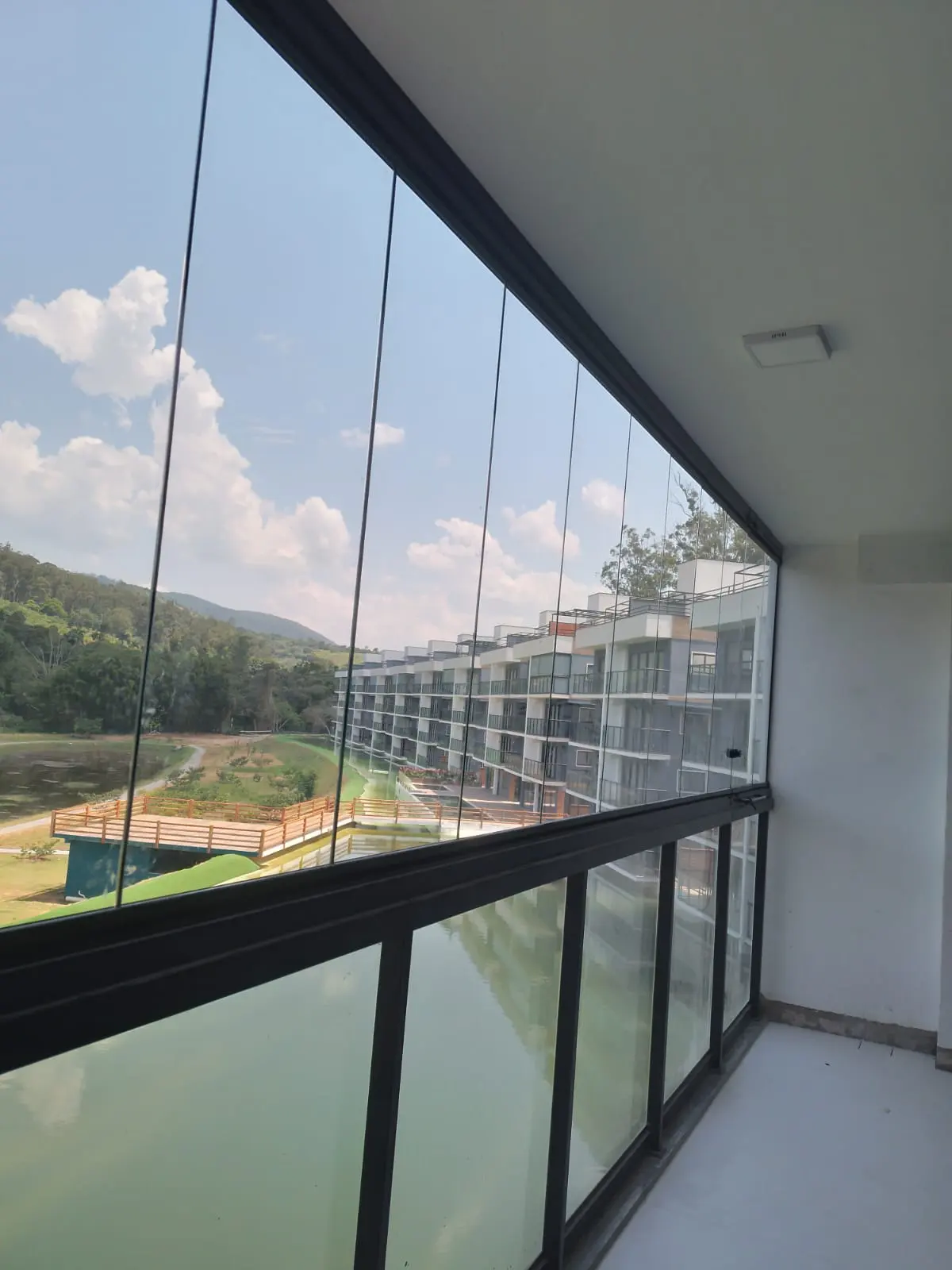 Sacada envidraçada com vista para lago, com perfis de alumínio anodizado