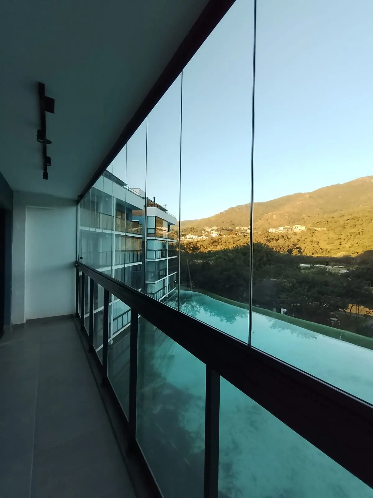 Sacada envidraçada com sistema retrátil recolhido na lateral, com vista para a serra