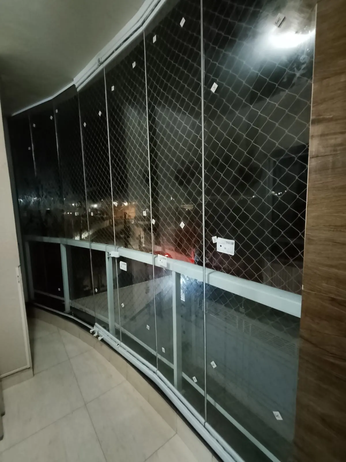 Sacada envidraçada iluminada à noite, com vista para a cidade