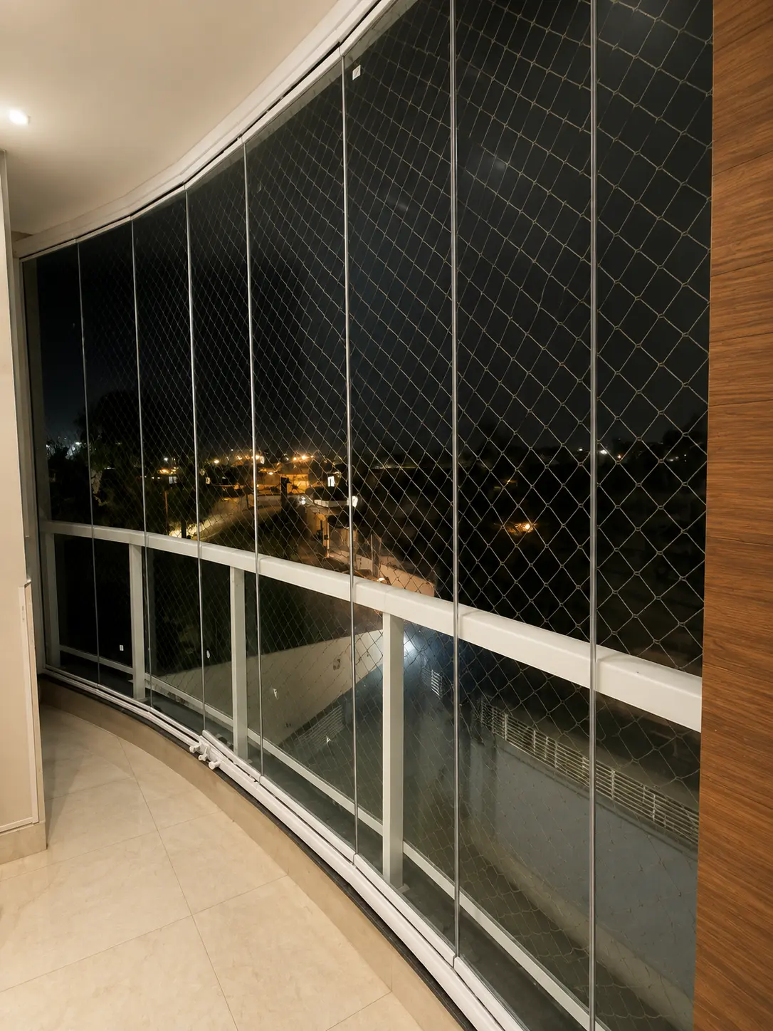 Sacada envidraçada com sistema de correr e tela de proteção, vista noturna da cidade