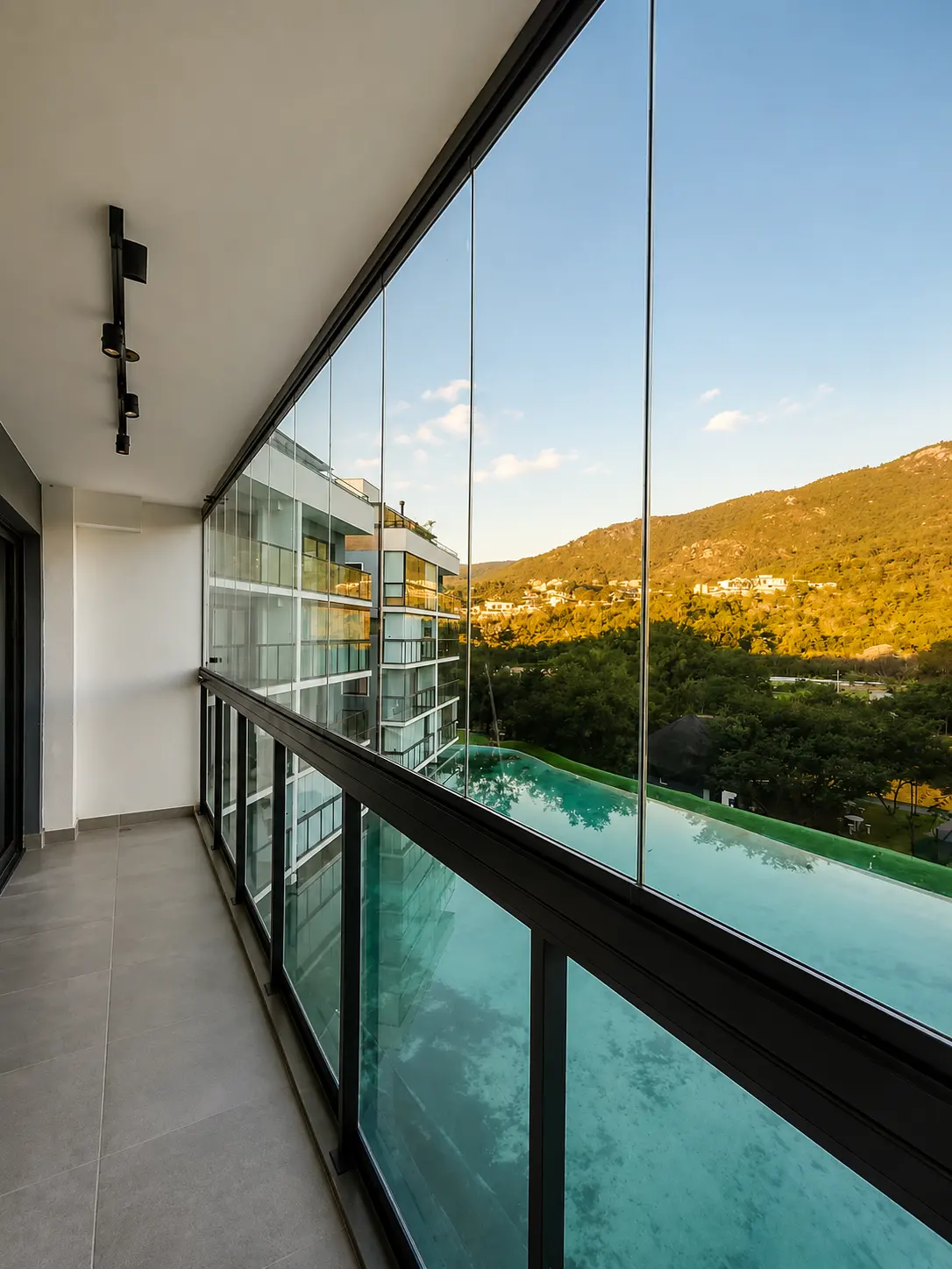 Varanda envidraçada com vidro temperado e perfil preto, com vista para piscina e serra